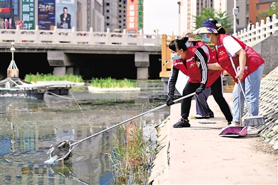 <p>　　　　银川市兴庆区银古路云和社区，工作人员在辖区内红花渠河段清理垃圾。本报记者　马楠　摄</p>